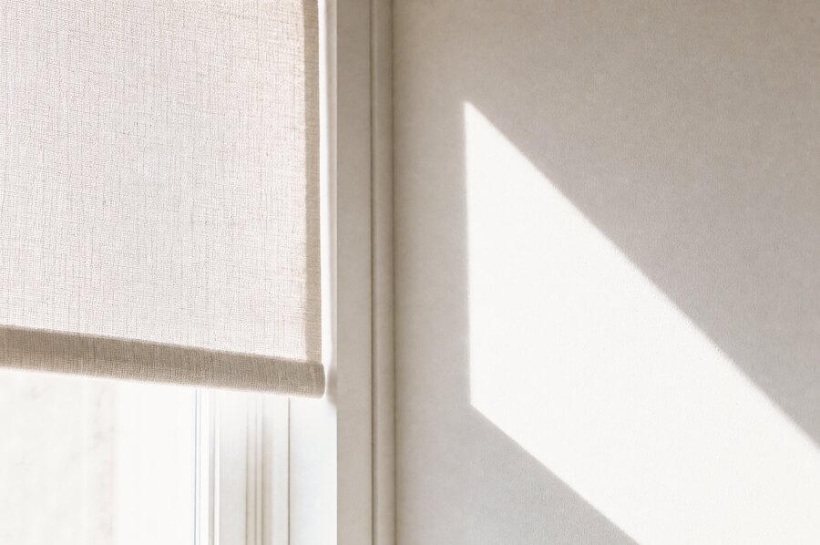 Ein halb heruntergelassenes Rollo, ein Lichtband auf heller Wand.